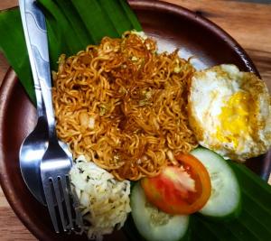 a plate of food with noodles and rice and a fork at Oma Watu Inn in Pringkuku