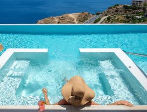 a woman in a hat swimming in a pool at Malvezzino Luxury Villas in Palaiokastro