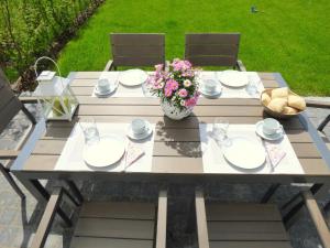 a picnic table with plates and a vase of flowers at Lindenstrasse Haus Sonnenrose in Zingst