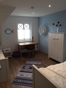 a bedroom with a desk and a window and a table at Lindenstr_ _Lille Hus 1_ in Zingst