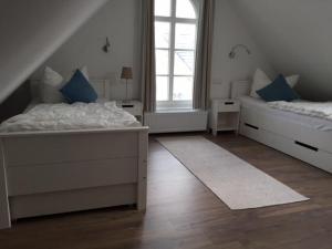 a bedroom with two beds and two windows at Lindenstr_ _Lille Hus 1_ in Zingst