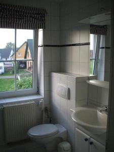 a bathroom with a toilet and a sink and a window at Deichweg in Zingst