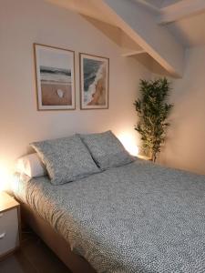 een slaapkamer met een bed met twee foto's aan de muur bij Appartement spacieux et moderne - Tout confort in Hendaye