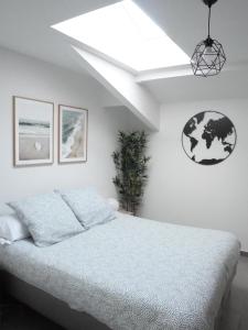 een witte slaapkamer met een bed en een dakraam bij Appartement spacieux et moderne - Tout confort in Hendaye