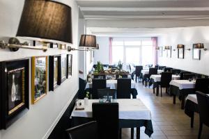 een restaurant met witte tafels en zwarte stoelen bij Pension Gérard in Bourbonne-les-Bains