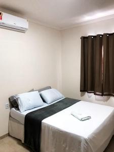 a bedroom with a bed with white sheets and a window at Hotel Bee's Sorriso in Sorriso