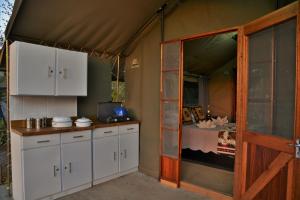 uma cozinha com armários brancos e uma cama numa tenda em Muchenje self-catering Tents em Chobe