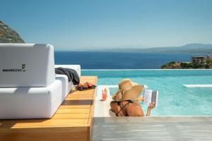 a woman in a hat reading a book in a swimming pool at Malvezzino Luxury Villas in Palaiokastro