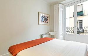 een witte slaapkamer met een bed en een raam bij BNBHolder Charming & Stylish III CHUECA in Madrid