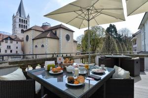 - une table avec de la nourriture sur un balcon avec un parasol dans l'établissement Apparthotel Privilodges Le Royal, à Annecy