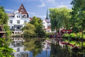 a river in a town with buildings and trees at Hotel Am Stadtpark in Buxtehude