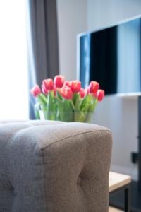 eine Vase roter Tulpen neben einer Couch in der Unterkunft APARTAMENTY LASER STUDIO in Stettin