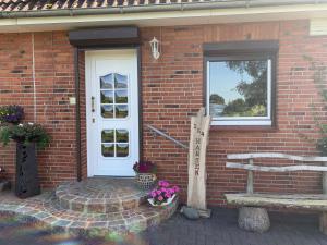 a brick house with a white door and flowers at Ferienhaus Karin in Erfde