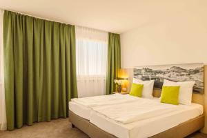 um quarto com uma cama grande e cortinas verdes em Highway Hotel em Herbolzheim