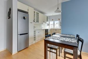 een keuken met een tafel met stoelen en een koelkast bij Comfort Apartments Abrahama in Gdynia
