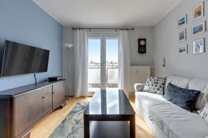 een woonkamer met een bank en een flatscreen-tv bij Comfort Apartments Abrahama in Gdynia