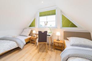 a attic room with two beds and a desk at Haus Bugspriet Haegerende in Zingst