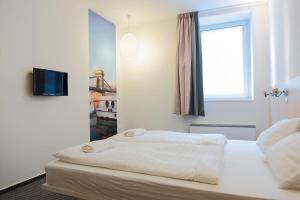 a bedroom with two beds and a television on a wall at Maverick Budapest Soho in Budapest