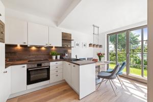 a kitchen with white cabinets and a table and chairs at Schulstr_ 15 _Sinja_ in Zingst