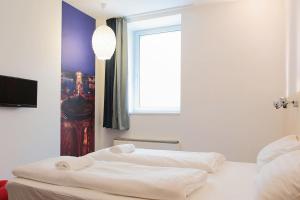 a bedroom with two beds and a window and a chandelier at Maverick Budapest Soho in Budapest