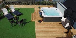um quintal com jacuzzi e duas cadeiras em Stunning Luxury Duplex with Hot Tub and AirCon em Glenfarg