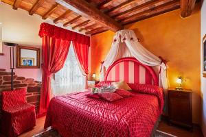 a bedroom with a red bed and a window at Podere la Casina Country Chic in Rigomagno
