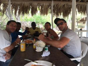 un grupo de personas sentadas en una mesa comiendo comida en Eco Hotel Bosque Encantado, en Isla Grande