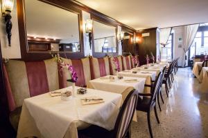 une rangée de tables dans un restaurant avec des nappes blanches dans l'établissement Victoria Hotel Letterario, à Trieste