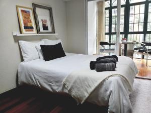 1 dormitorio con 1 cama blanca grande con almohadas negras en COLLECTION CITY - Bed & Breakfast, Alicante Center I Cocina & Amplia Terraza - Jardín, en Alicante