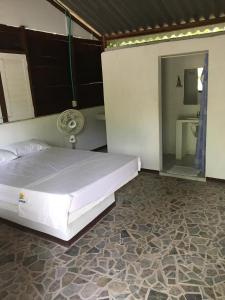 a bedroom with a white bed and a bathroom at Eco Hotel Bosque Encantado in Isla Grande