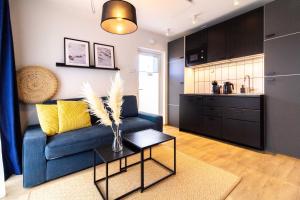 a living room with a blue couch and a kitchen at Green Shine Apartment, By Cohost in Palanga