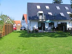 a white house with a fence and a grass yard at Schulstrasse 10a Fewo in Zingst