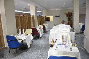 un comedor con mesas y sillas blancas en Hotel Royal Palace en Duala