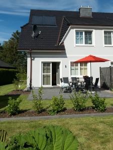a white house with a table and chairs and an umbrella at Hirtenweg in Zingst