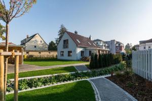 um jardim com uma casa branca e uma cerca branca em Buten un Binnen em Zingst