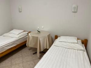 a room with two beds and a table with flowers on it at Part Cafe Residence in Dunakeszi