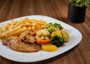 a plate of food with french fries and chicken and vegetables at ibis Betim in Betim