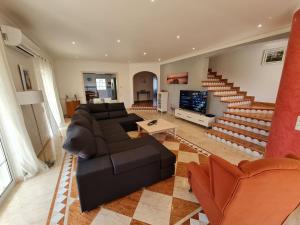 ein Wohnzimmer mit einer Couch und einem Fernseher und Treppen in der Unterkunft Villa Duartes in Altura