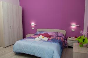 una camera con una parete viola e un letto di Rainbow B&B a Campofelice di Roccella