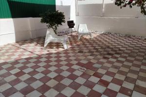 2 chaises blanches assises sur un sol en damier dans l'établissement Memoria 49 TERRACE, à Lisbonne