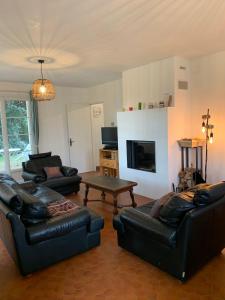 uma sala de estar com mobiliário de couro preto e uma televisão em Villa Yeure em Camiers