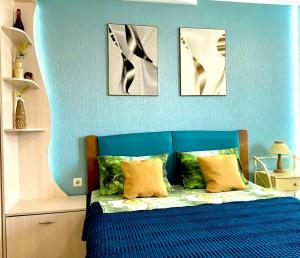 a blue bedroom with a bed with four pictures on the wall at Cozy studio in Vinnytsya
