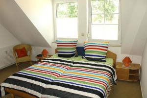 ein Schlafzimmer mit einem Bett mit einer bunten gestreiften Decke in der Unterkunft Birkenstr.6 Haus 1 Bodden Pirat in Zingst