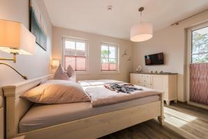a bedroom with a bed and a dresser and two windows at Viktoria Luna WE 8 Kuestenzauber in Zingst
