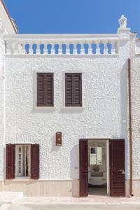Biały budynek z brązowymi okiennicami w obiekcie Stella Bianca w mieście Savelletri di Fasano