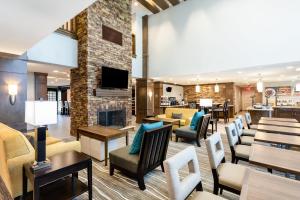 a lobby with chairs and tables and a fireplace at Staybridge Suites - Fort Lauderdale Airport - West, an IHG Hotel in Davie