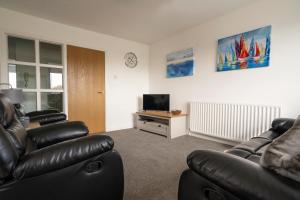 een woonkamer met 2 leren banken en een televisie bij The Loft, Cloughey in Kirkistown