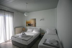 two beds in a white room with towels on them at Pharos Apartments in Gavrio