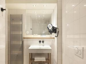 a white bathroom with a sink and a mirror at Townhouse Hotel Maastricht & Spa in Maastricht +71 photos
