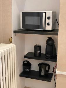 a microwave on a shelf next to a heater at Chambre de la Poterie in Accolay